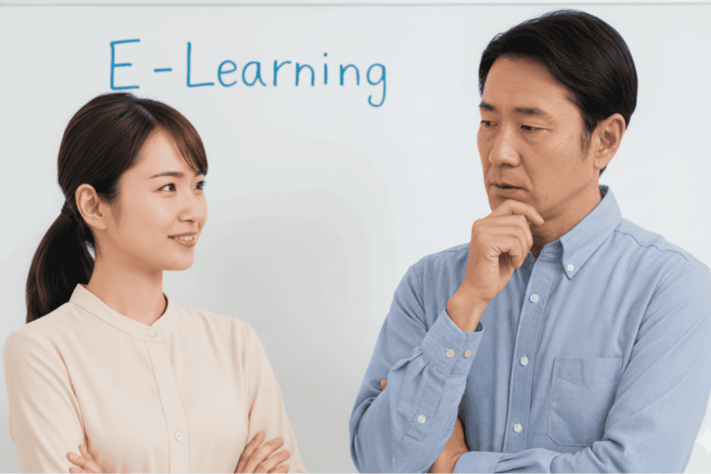 ホワイトボードに書かれた「E-Learning」の文字を背に、導入や活用について真剣な表情で話し合う男女の画像